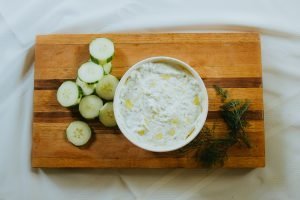 tzatziki sauce on a white cutting board with cucumber next to it