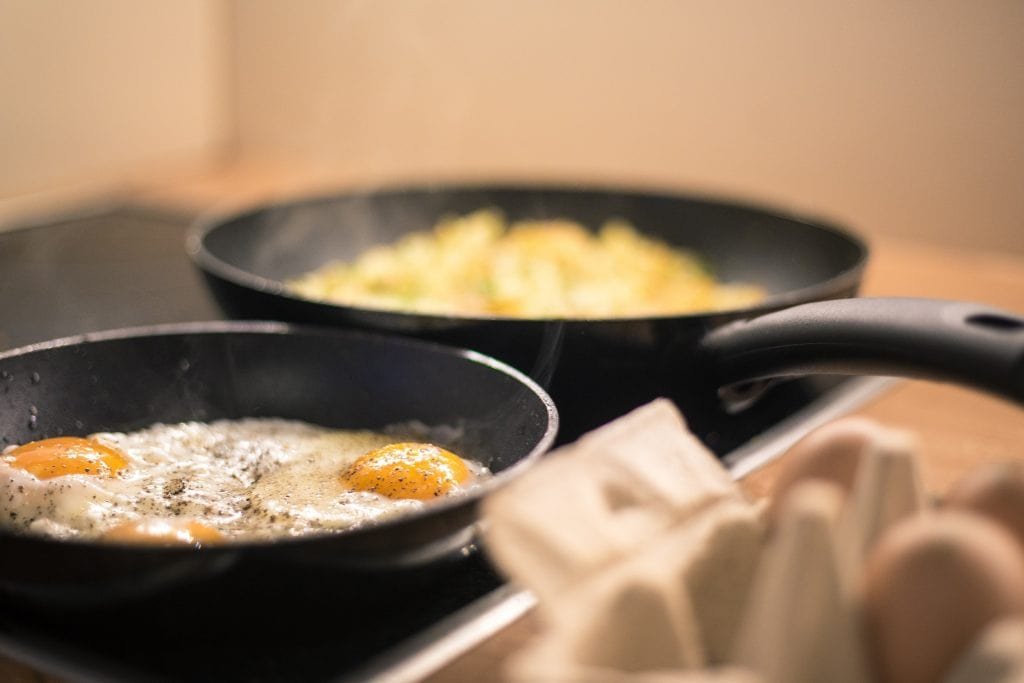 Eggs frying in two non-stick pans.
