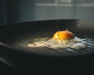 Egg is cracked into an open frypan.