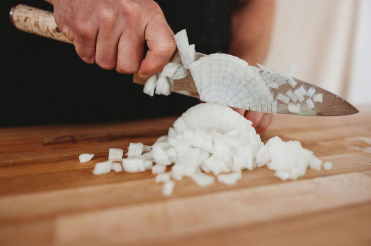 person cutting onions with miyabi knife