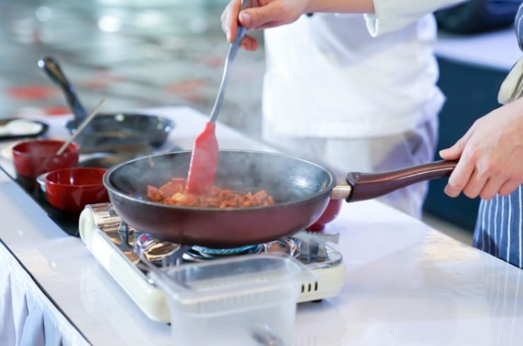 person cooking food in a red pan