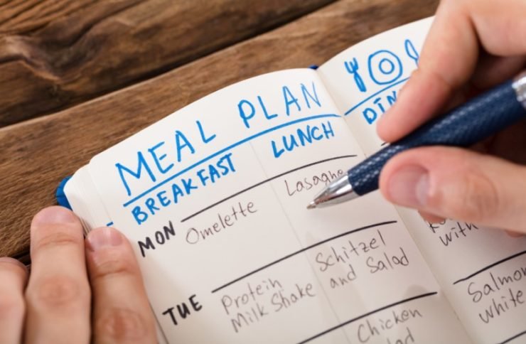 person planning meals in a notebook