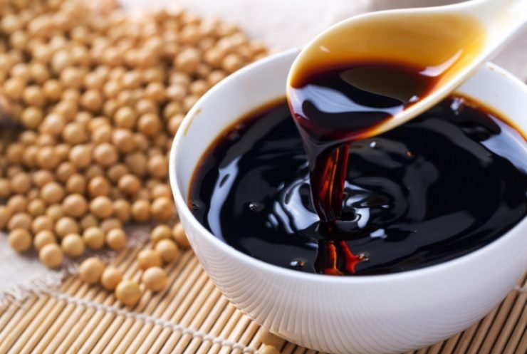 soy sauce in a white bowl with soy seed in background