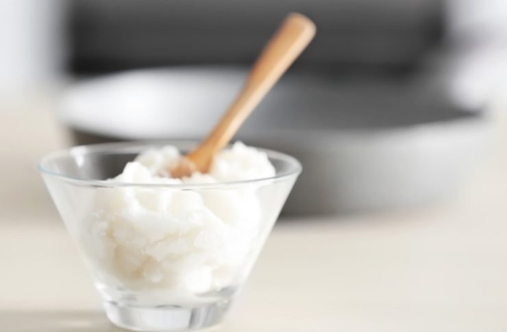 coconut oil in a glass bowl with a wooden spoon