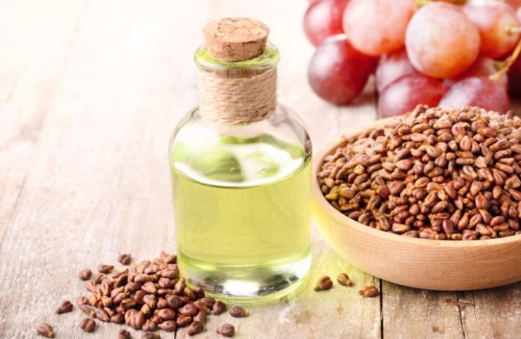 grapeseed oil in a jug next to a bowl of grapeseeds