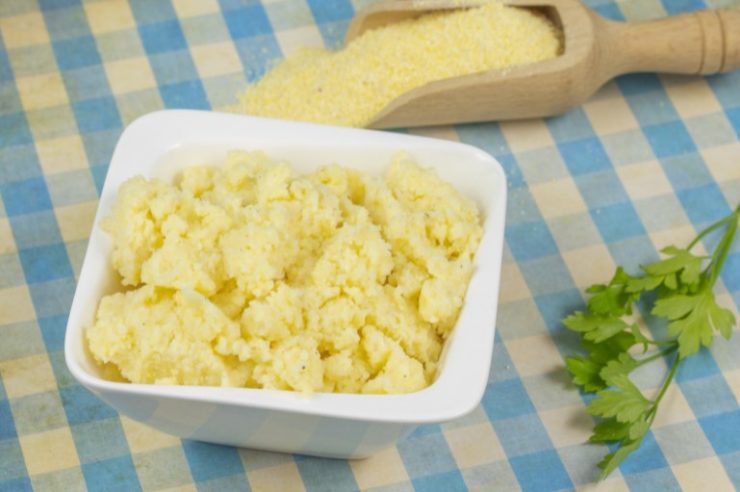 polenta in a white bowl and polenta flour behind it