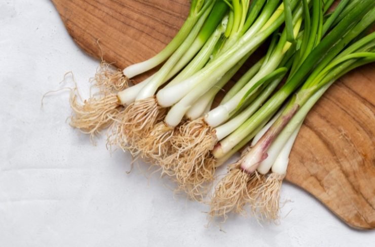 bunch of scallions on a wooden cuting board