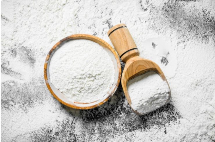 all purpose flour spilled on a table and a bowl of all purpose flour on top of it