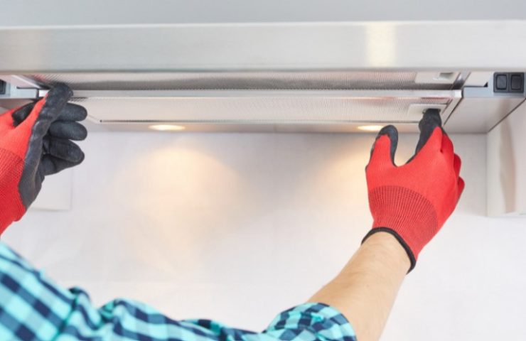 man wearing red gloves instaling a range hood filter