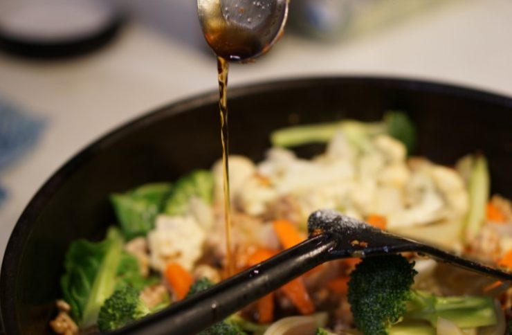 Cooking and pouring sauce into Asian stir fry.