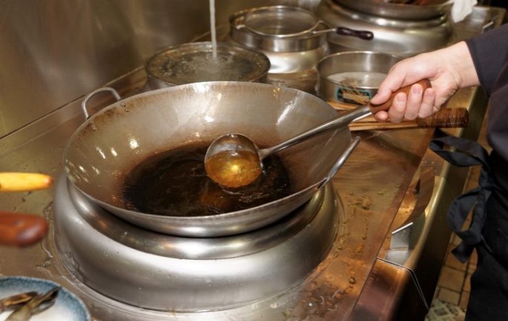 Chef is pouring cooking oil in wok