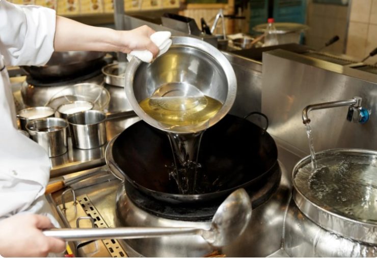 Chef is pouring cooking oil in wok