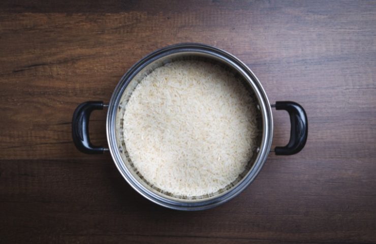 Jasmine rice in pot on wooden background.