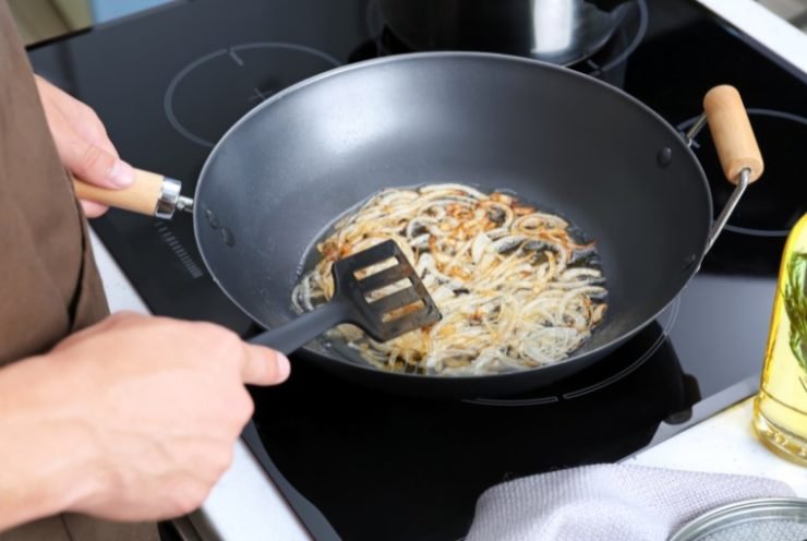 Man Frying Onion in a Wok on the Stove