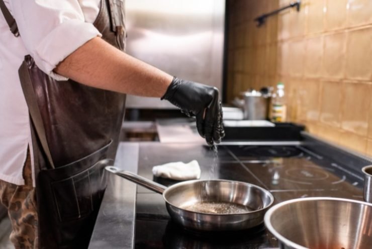 chef adding salt to  a pan