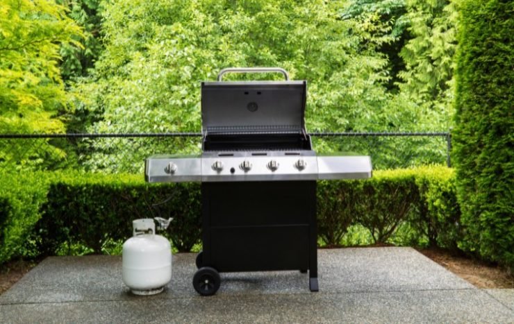 Gas grill with white tank on outdoor patio