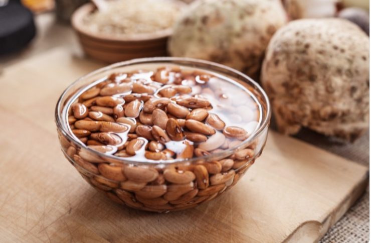 soaked beans in glass bowl on wooden surface