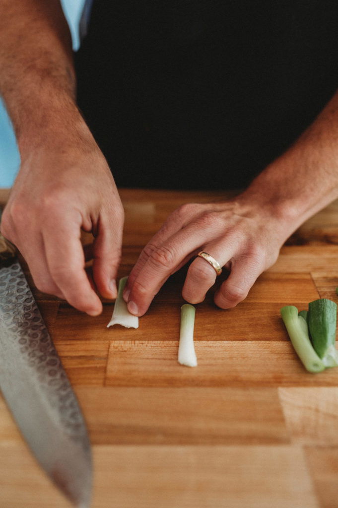 person cutting green onions into half moons