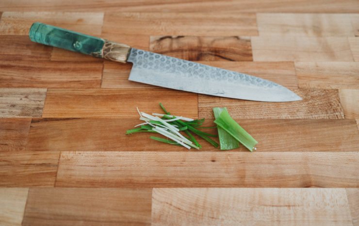 julienne green onions on a wooden cutting board
