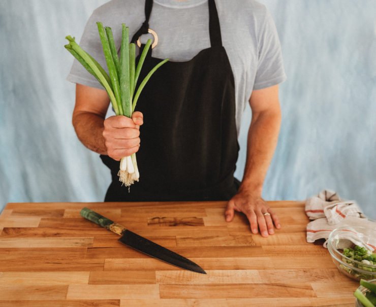 person holding whole green onions
