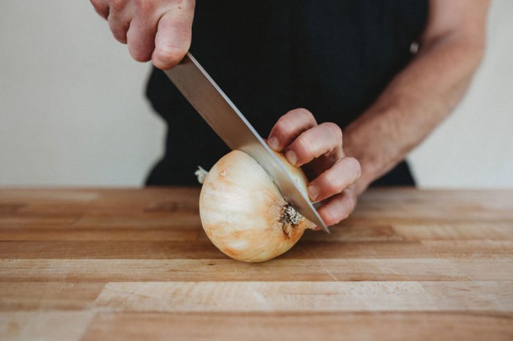 person cutting onion in half