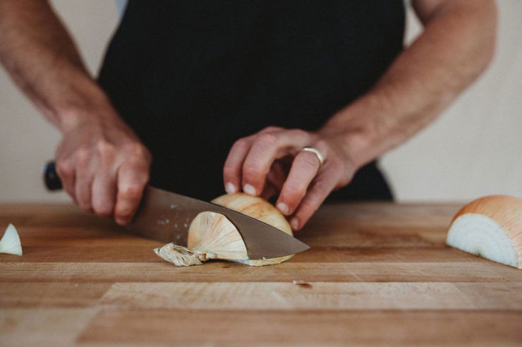 person cutting the tip of onion