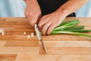 person cutting green onions into rounds