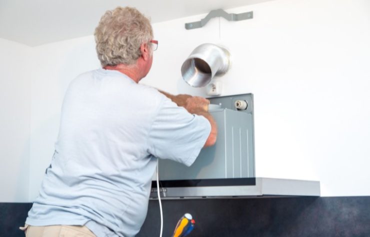 Fitter men installing range hood in new kitchen