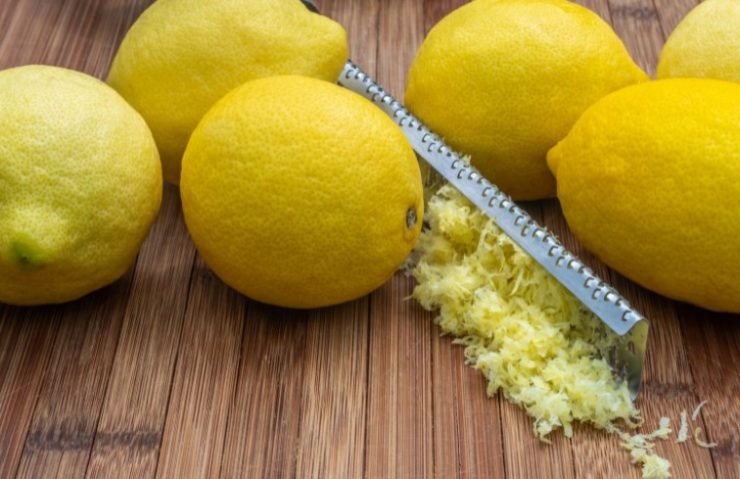 Ripe lemons with zest and grater on table
