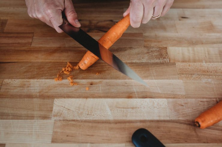 person peeling carrot with a knife