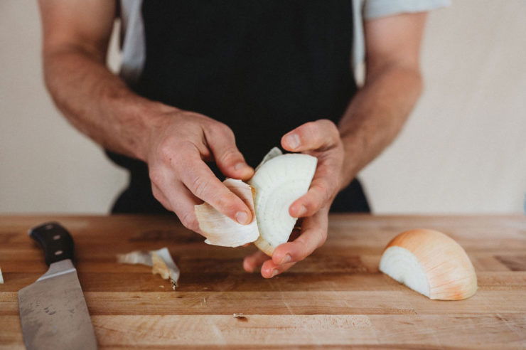 person peeling onions by hand