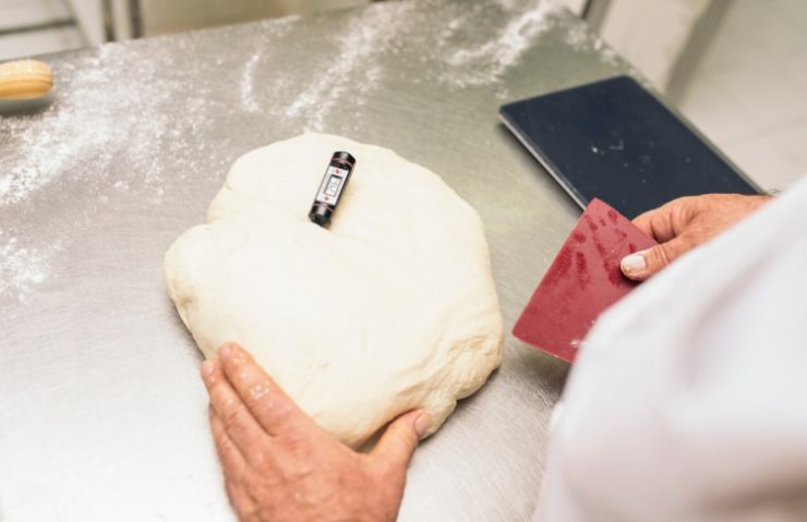 Baker kneading dough in a bakery.