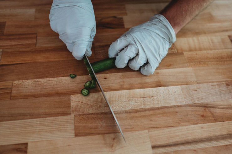 chef wearing gloves while chopping pepper