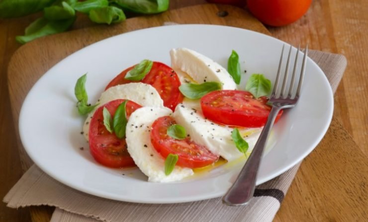 tomato, mozzarela and basil on a white plate