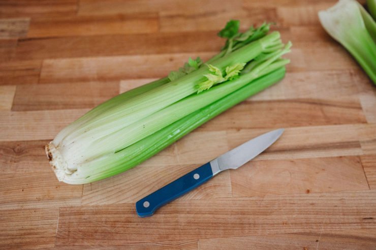 celery and knife on a wooden cutting board