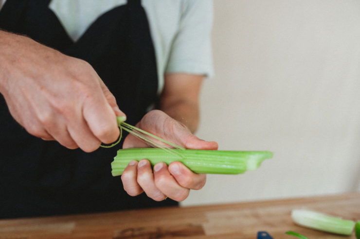 person peeling celery with hand