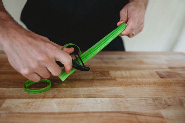 person peeling celery with vegetable peeler