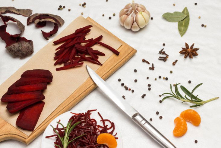 Sliced fermented beets. Sliced fresh beets and knife on cutting board.