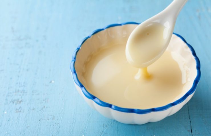 Bowl with pouring condensed milk or evaporated milk.