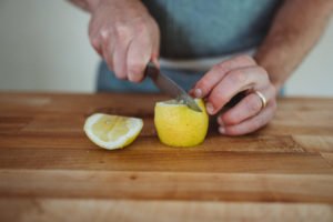 person cutting lemon on a cutting board