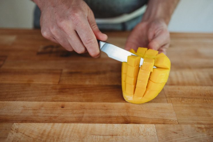 person cutiing mango off the peel