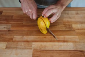 person cutting half of a mango