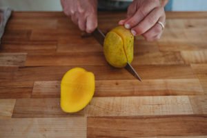 person cuting mango into half
