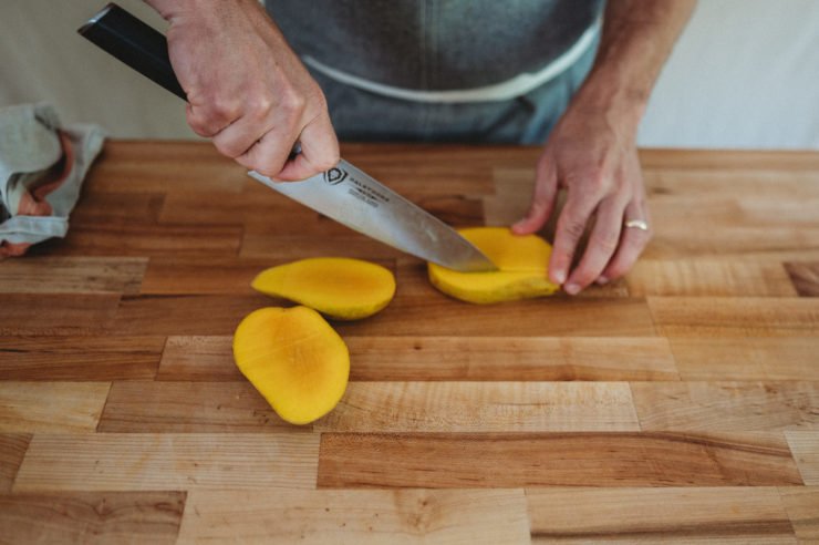 person cutting mango sides