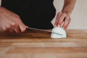 cutting onion on a wooden cutting board