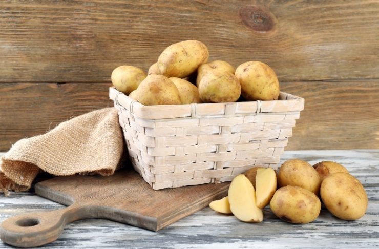 Young Potatoes in Wicker Basket on Wooden Table