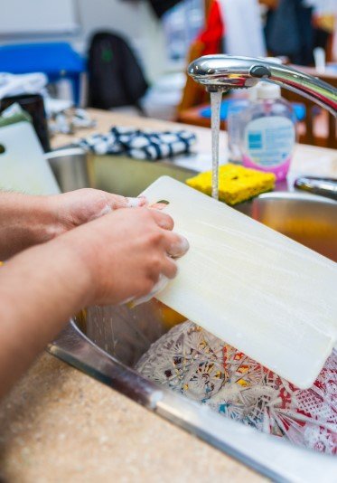 Soapy Hands Washing Cutting Board at a Kitchen Sink