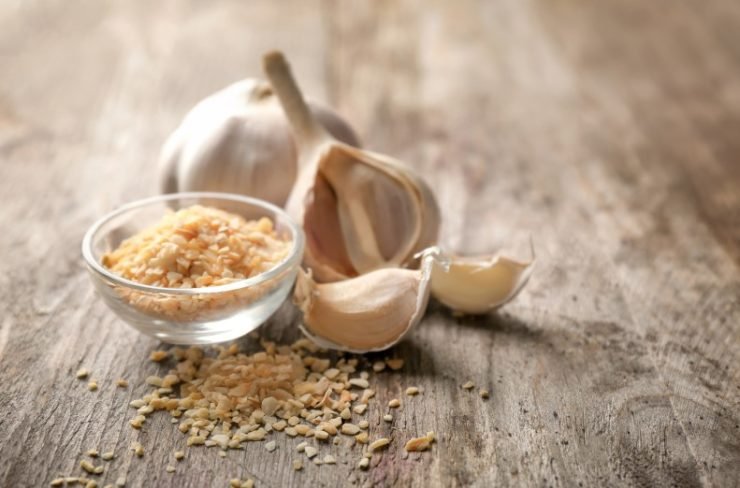 Bowl with Granulated Dried Garlic on Wooden Background