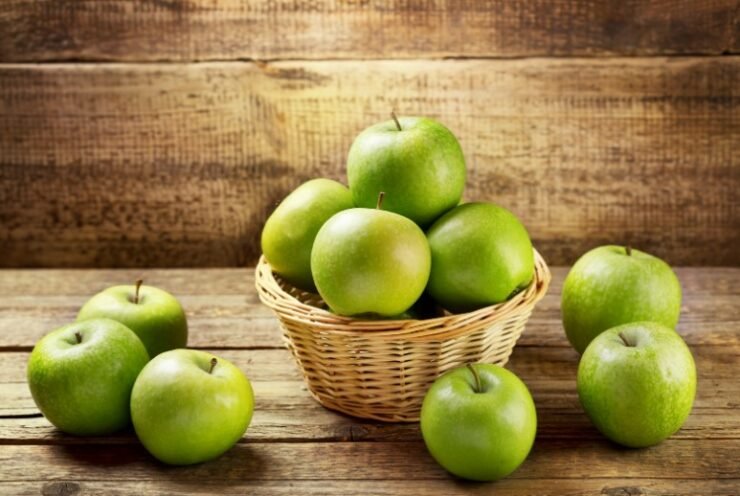 a bunch of green apples in a basket