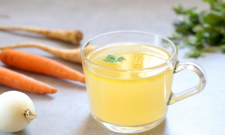 Bone broth with vegetables in a glass bowl